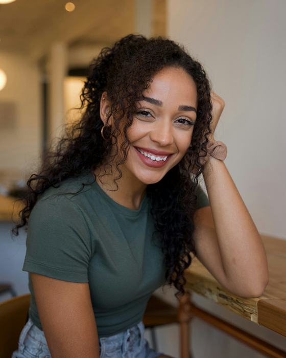 A smiling woman sitting at a wooden table